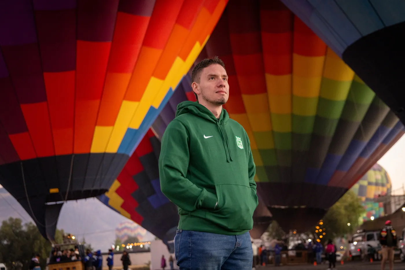 Young man beneath a colorful balloon before the flight, ring proposal at sunrise