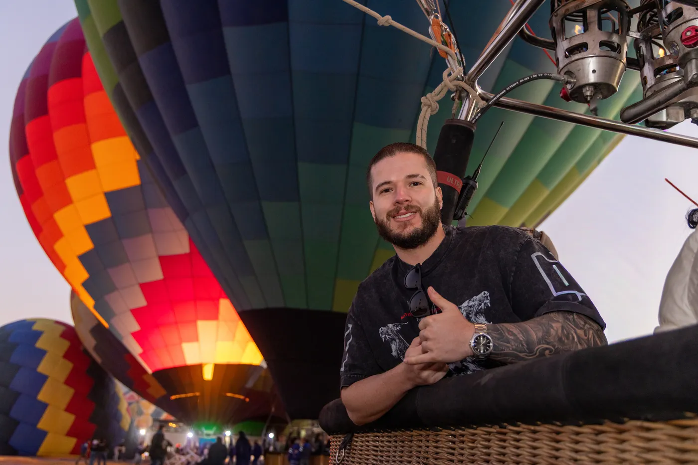Pasajero sonriente en la canastilla mientras los globos se inflan al amanecer